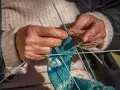 Dłonie tworzą wzorzysty tricot na drutach.