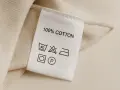 Metka odzieżowa z napisem "100% COTTON" i symbolami pielęgnacji.