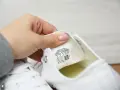 Porównanie converse oryginalne a podróbki. Dłoń pokazuje metkę z rozmiarem na białym bucie.
