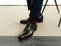Eleganckie czarne buty męskie, rozmiar buta 50, z bordowymi skarpetkami i granatowymi spodniami.