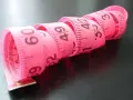 Różowa taśma miernicza zwinięta w spirale, z widocznymi numerami, jak na elefanten tabela rozmiarów.