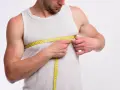 Mężczyzna mierzy obwód klatki piersiowej żółtą miarką.