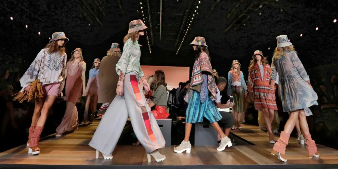 Pokaz mody BCBGMAXAZRIA. Modelki prezentują kolorowe, etniczne stroje i kapelusze na wybiegu.