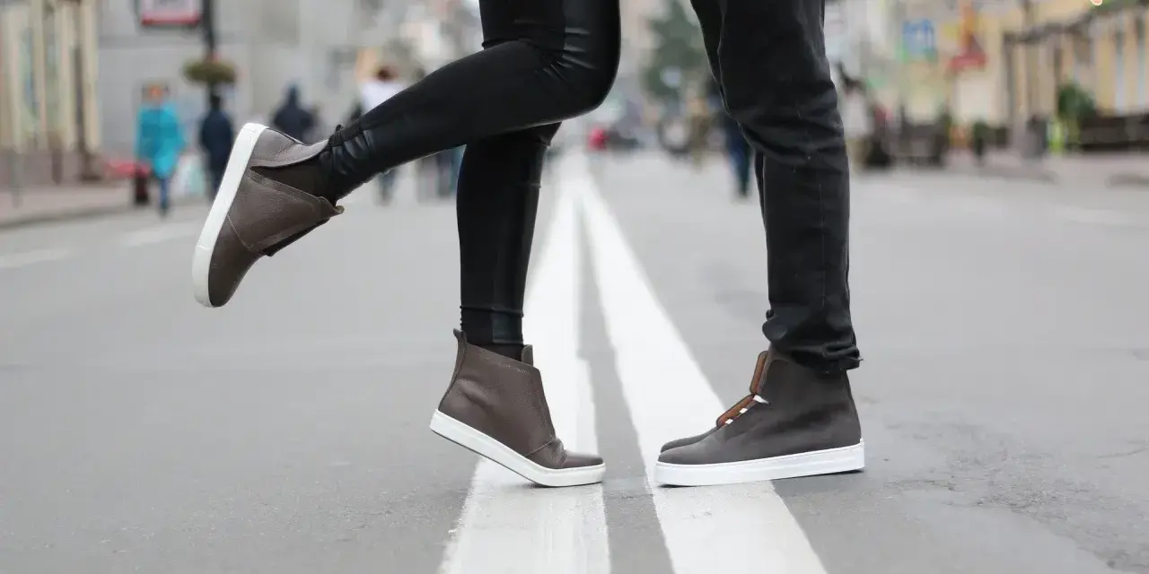 Para, jak zapobiec farbowaniu butów? Stylowe brązowe sneakersy na miejskim przejściu dla pieszych.