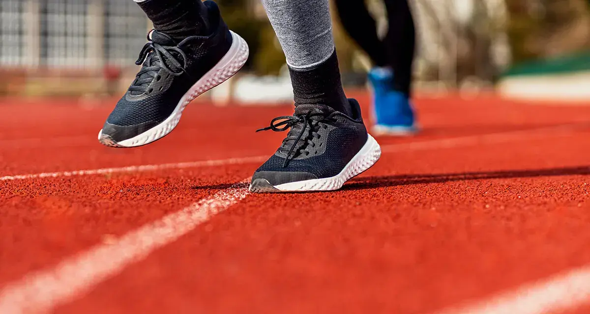 Biegacze na bieżni. Widoczne buty sportowe, podkreślające ruch stopy, czyli supinację i pronację.