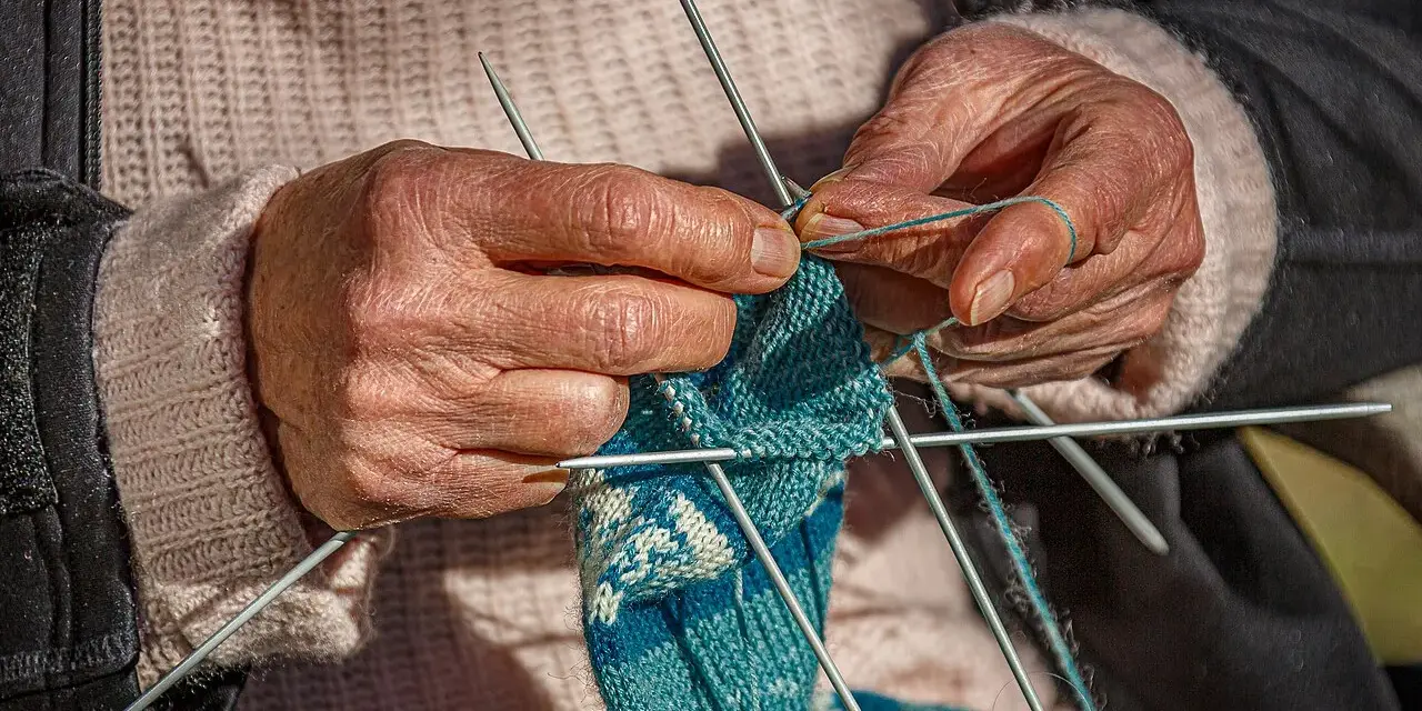 Dłonie tworzą wzorzysty tricot na drutach.