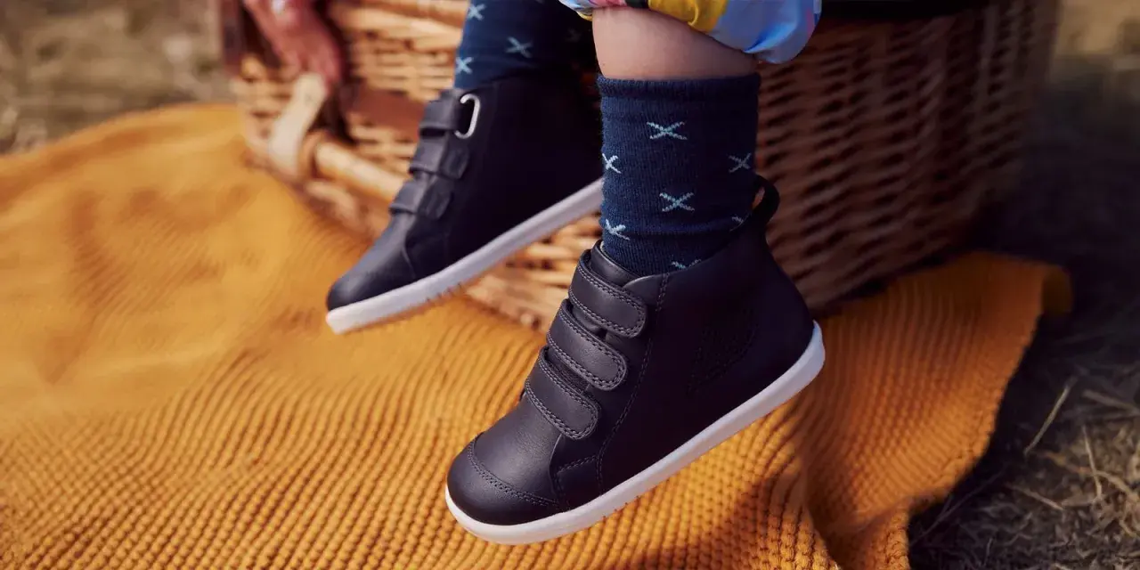 Dziecięce buty zimowe na rzepy, na tle koszyka piknikowego i koca.
