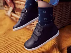 Dziecięce buty zimowe na rzepy, na tle koszyka piknikowego i koca.