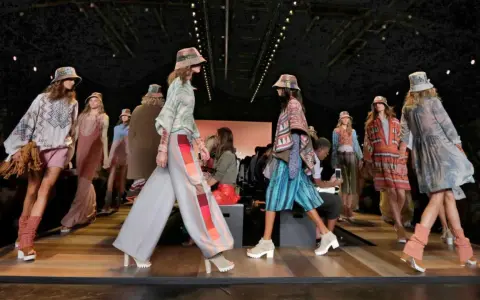 Pokaz mody BCBGMAXAZRIA. Modelki prezentują kolorowe, etniczne stroje i kapelusze na wybiegu.