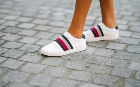 Białe trampki z kolorowymi paskami, rozmiar us 7, na brukowanej ścieżce.