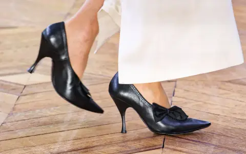 Eleganckie czarne szpilki z kokardką i frędzelkami. Takie buty są teraz modne, idealne do białych spodni.