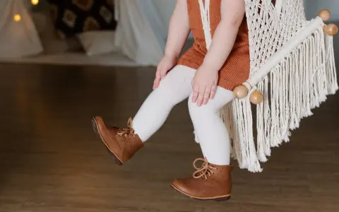 Małe nóżki w brązowych bucikach, idealne na spacer. Jaki to rozmiar buta dziecka?