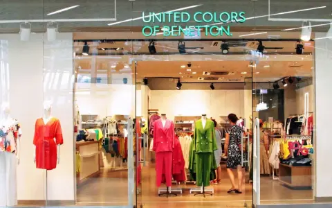 Witryna sklepu United Colors of Bennetton z kolorowymi ubraniami na manekinach i wieszakach.
