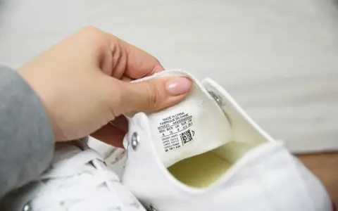 Porównanie converse oryginalne a podróbki. Dłoń pokazuje metkę z rozmiarem na białym bucie.
