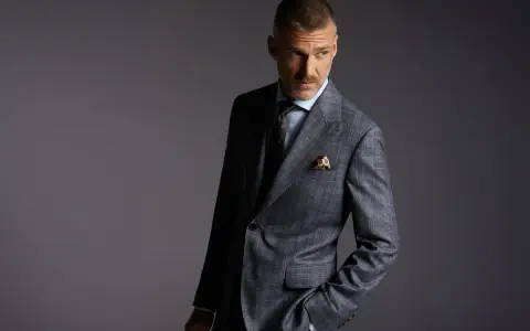 Elegancki mężczyzna w garniturze w kratę. Czy to Dressmann? To firma oferująca modną odzież męską.