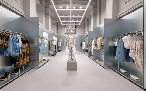 Nowoczesne wnętrze sklepu Bershka z wieszakami pełnymi ubrań i manekinem w centrum.