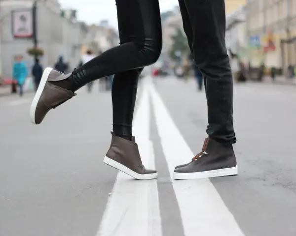 Para, jak zapobiec farbowaniu butów? Stylowe brązowe sneakersy na miejskim przejściu dla pieszych.