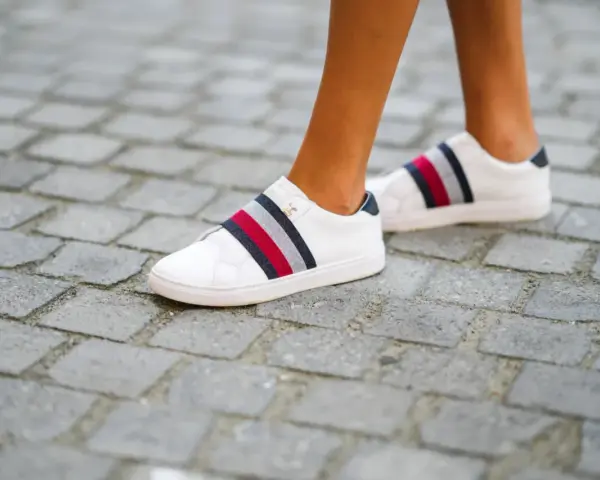 Białe trampki z kolorowymi paskami, rozmiar us 7, na brukowanej ścieżce.