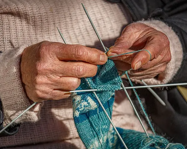 Dłonie tworzą wzorzysty tricot na drutach.