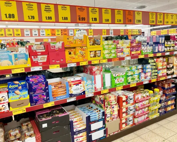 Półki sklepowe uginają się od słodkości, ciastek i herbat. Widać tu wiele produktów marki newcential, w tym ciastka, wafle i herbaty w atrakcyjnych cenach.