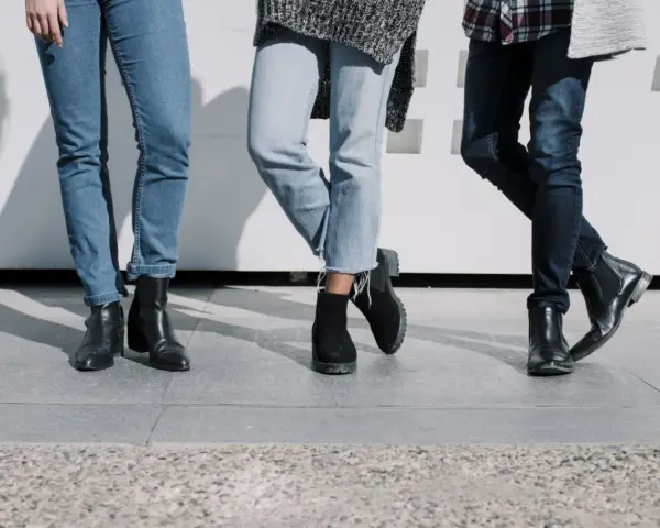 Trzy pary damskich jeansów i różne buty: botki na obcasie, zamszowe botki i eleganckie botki. Idealne inspiracje, jakie buty do jeansów damskich wybrać.