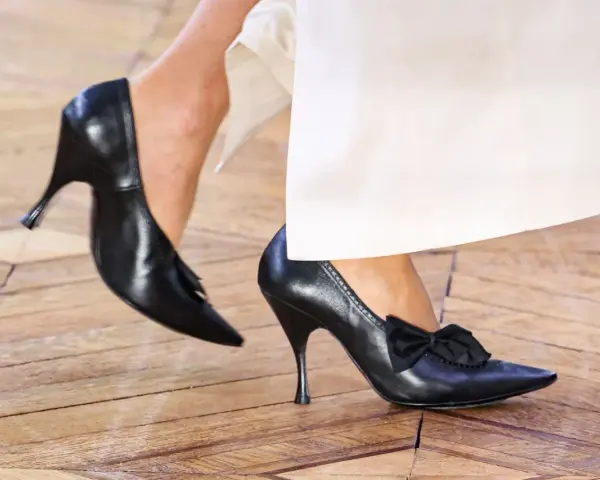 Eleganckie czarne szpilki z kokardką i frędzelkami. Takie buty są teraz modne, idealne do białych spodni.