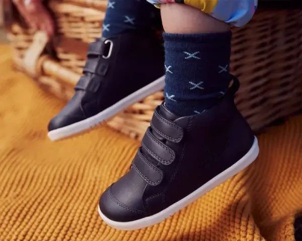 Dziecięce buty zimowe na rzepy, na tle koszyka piknikowego i koca.