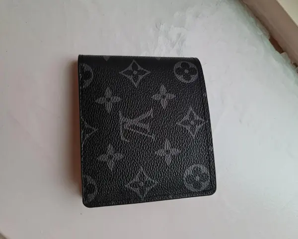 Czarny portfel Louis Vuitton z monogramem na jasnym tle.