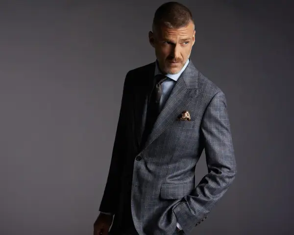 Elegancki mężczyzna w garniturze w kratę. Czy to Dressmann? To firma oferująca modną odzież męską.