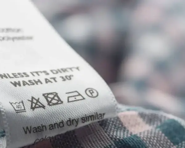 Metka z instrukcją prania: prać w 30°C, nie wybielać, prasować w niskiej temperaturze, dopuszczalne czyszczenie chemiczne.