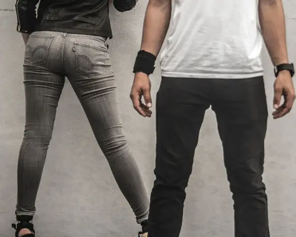 Szara, dopasowana para jeansów, widać metkę Levi's. Czy to rozmiar w25? Obok mężczyzna w czarnych spodniach.