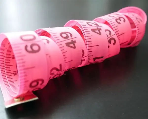 Różowa taśma miernicza zwinięta w spirale, z widocznymi numerami, jak na elefanten tabela rozmiarów.