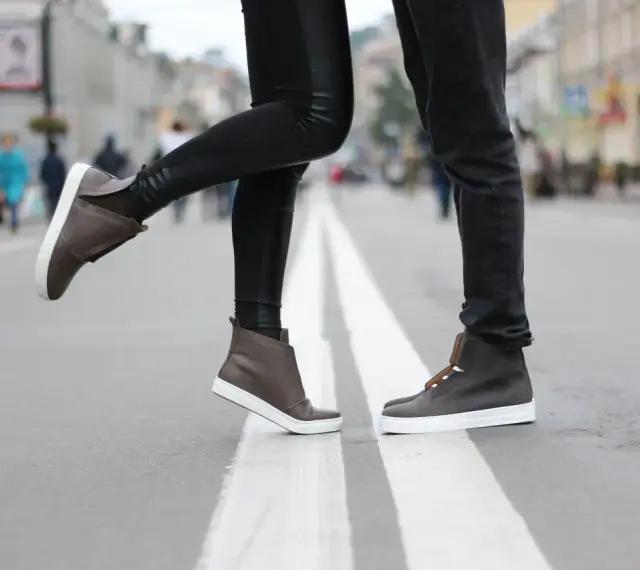 Para, jak zapobiec farbowaniu butów? Stylowe brązowe sneakersy na miejskim przejściu dla pieszych.