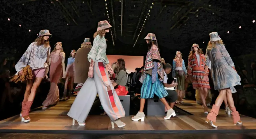 Pokaz mody BCBGMAXAZRIA. Modelki prezentują kolorowe, etniczne stroje i kapelusze na wybiegu.