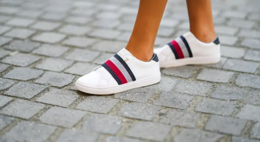 Białe trampki z kolorowymi paskami, rozmiar us 7, na brukowanej ścieżce.