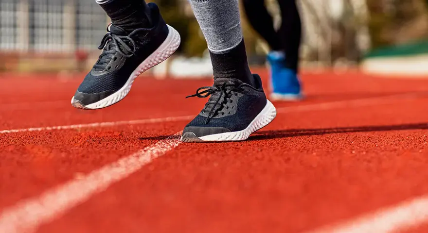 Biegacze na bieżni. Widoczne buty sportowe, podkreślające ruch stopy, czyli supinację i pronację.