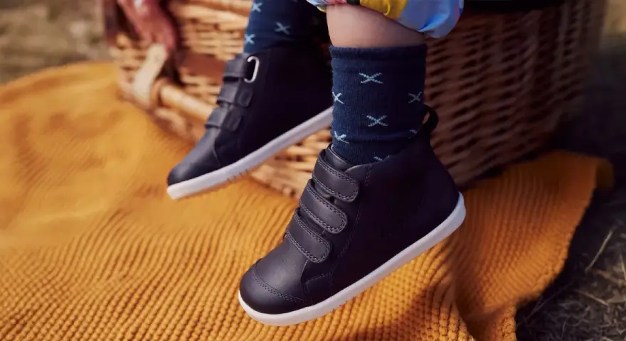 Dziecięce buty zimowe na rzepy, na tle koszyka piknikowego i koca.