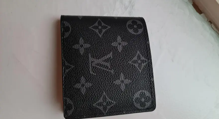 Czarny portfel Louis Vuitton z monogramem na jasnym tle.