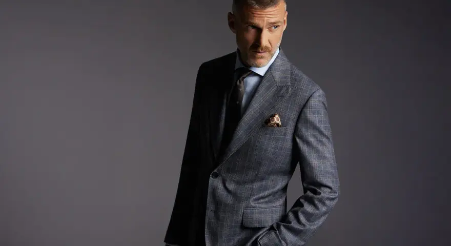 Elegancki mężczyzna w garniturze w kratę. Czy to Dressmann? To firma oferująca modną odzież męską.