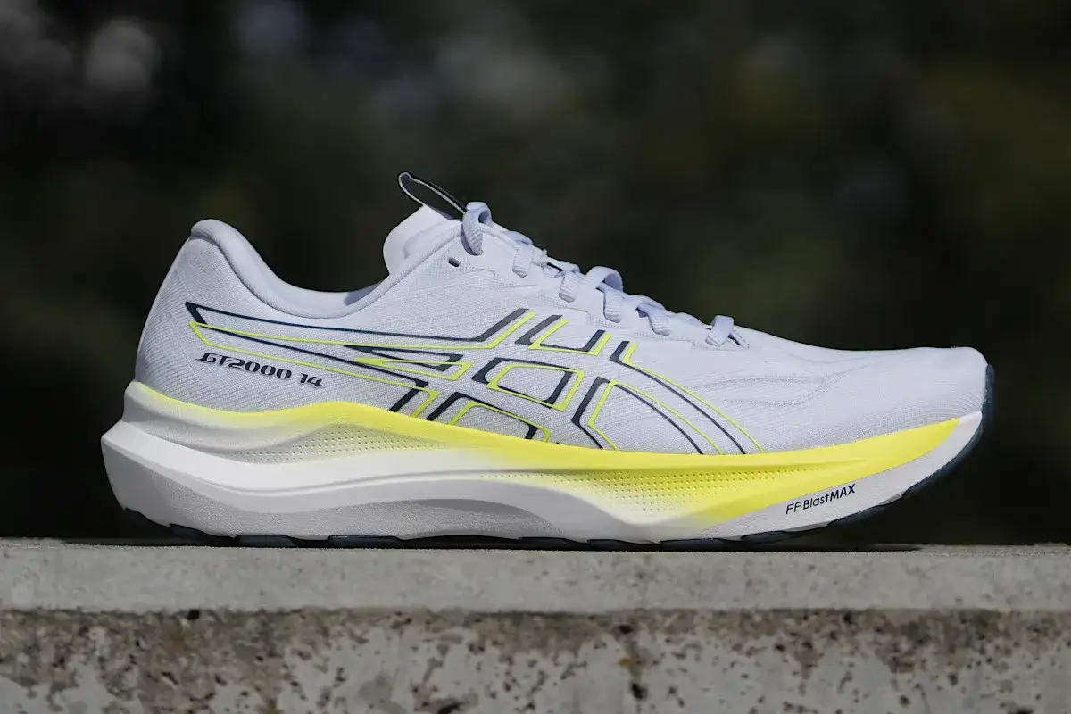 Biały but biegowy Asics GT-2000 14 z żółtymi akcentami. Asics to znana firma produkująca obuwie sportowe.
