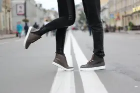 Para, jak zapobiec farbowaniu butów? Stylowe brązowe sneakersy na miejskim przejściu dla pieszych.