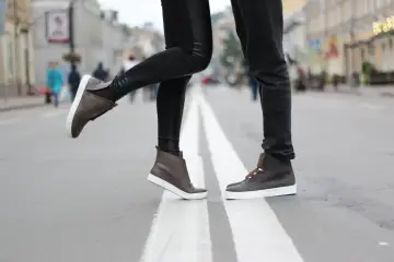 Para, jak zapobiec farbowaniu butów? Stylowe brązowe sneakersy na miejskim przejściu dla pieszych.
