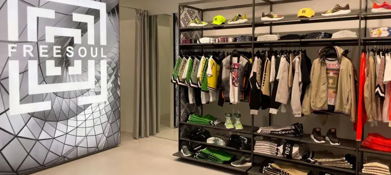 Sklep z odzieżą freesoul co to za firma. Widać ubrania i buty tej marki, a także logo freesoul na ścianie.